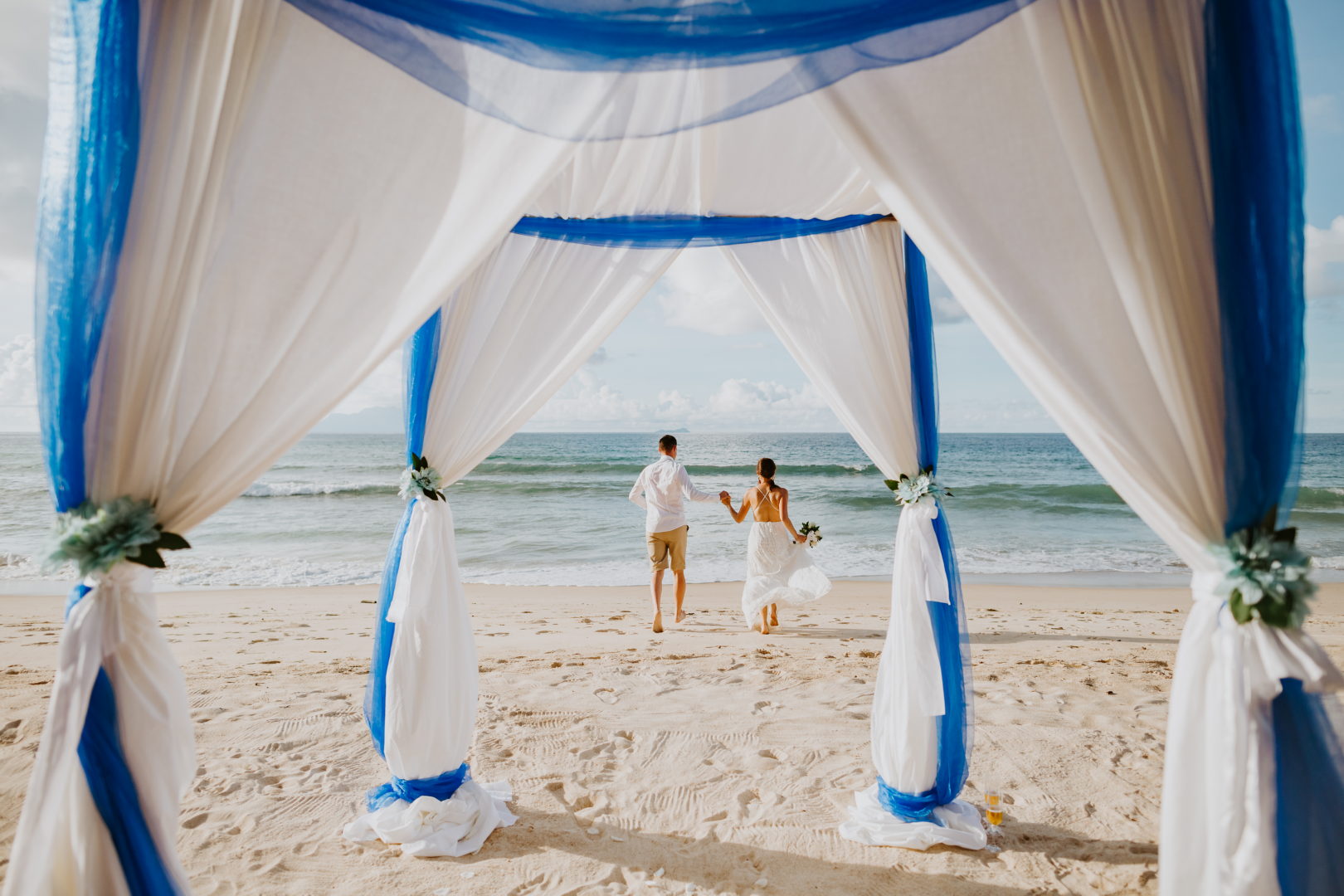 beach wedding in tropics. Wedding couple on beach with wedding arch background. Destination wedding on the island with sea view.