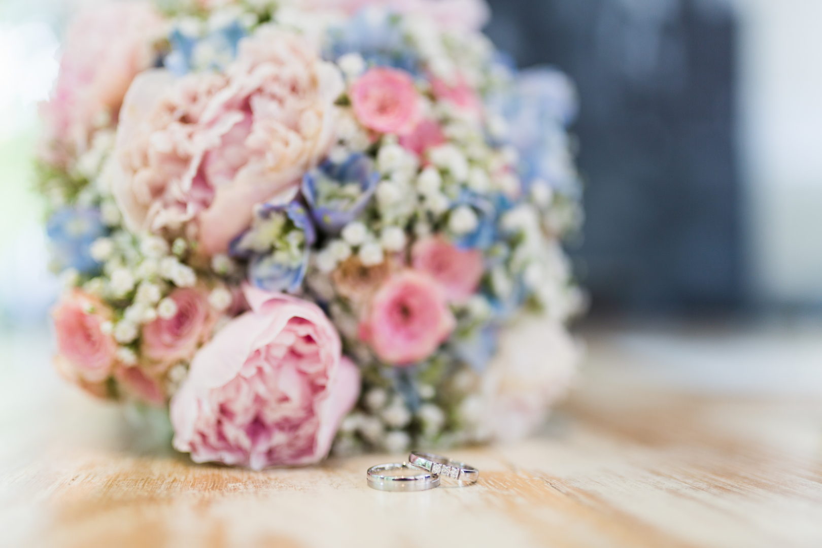 A closeup shot of a marriage rings near a flower bouquet with a blurred background